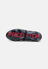 Zwarte voetbalschoenen met een textiele bovenkant, een flexibele pasvorm en een doorzichtige zool met rode "PREDATOR" branding.
