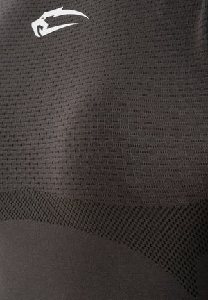 Gros plan sur un tissu sombre texturé avec un petit motif en maille et un logo blanc stylisé en forme de griffe ou patte d'animal près du coin supérieur gauche.