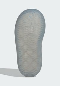 Semelle de chaussure en matériau en caoutchouc translucide présentant une texture et un motif ondulés, principalement claire avec des accents bleus.