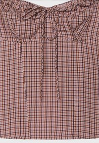 Blouse en tissu à carreaux rose et marron avec encolure froncée, lien à l’avant et détail subtil de volants le long du bord supérieur.