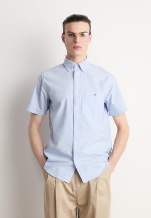 Camicia azzurra chiara a maniche corte con bottoni e tasca, realizzata in cotone. Presenta una vestibilità slim e un sottile ricamo sul petto.