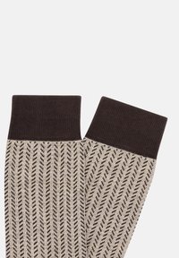 Knästrumpor med en texturerad brun manschett och en ljusbeige kropp med ett diagonalt randmönster i mörkbrunt.