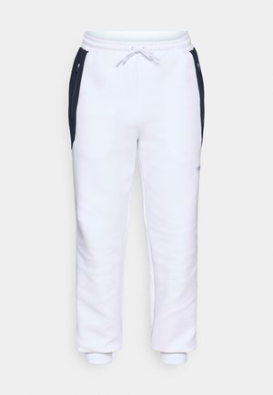 White sweatpants with a drawstring waist, featuring black side panels, elastic cuffs, and a small logo on the lower leg. Soft fabric texture.
