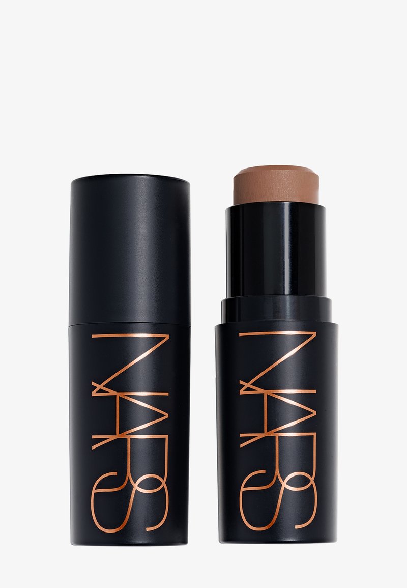 Bâton de maquillage noir NARS avec son capuchon enlevé, montrant un produit crème marron à l’intérieur, à côté du capuchon fermé sur fond blanc.