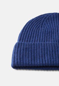 Knit beanie in dark blue wool with vertical ribbed texture, featuring a folded cuff at the bottom. Soft and warm fabric.