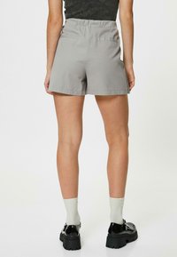 Grå shorts med elastisk midja, som har två bakfickor. Bärs tillsammans med svarta plattforms skor och ljusgrå strumpor.