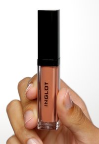 Lipgloss i en klar tub med ett svart lock. Nyansen är en mjuk nude. Varumärket "INGLOT" visas vertikalt på sidan. Slät textur.