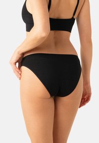 Bas de bikini en coton noir avec une texture lisse et une coupe classique, doté d'une taille haute et de coutures minimales pour le confort.