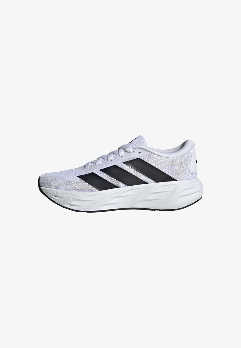 Chaussure de sport blanche avec des bandes Adidas noires, empeigne en mesh, semelle épaisse et rembourrée, et lacets à l'avant, vue de côté sur fond blanc.