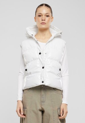 Puffervest in glanzend wit materiaal met capuchon, voorzien van zwarte knopen, een doorgestikt ontwerp en een korte silhoeet. Gecombineerd met een lange mouwen shirt.