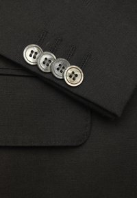 Czarna tkanina o gładkiej fakturze z klapą marynarki i czterema guzikami, dwoma metalowymi i dwoma z czarnego plastiku, z naszytym detalem powyżej.