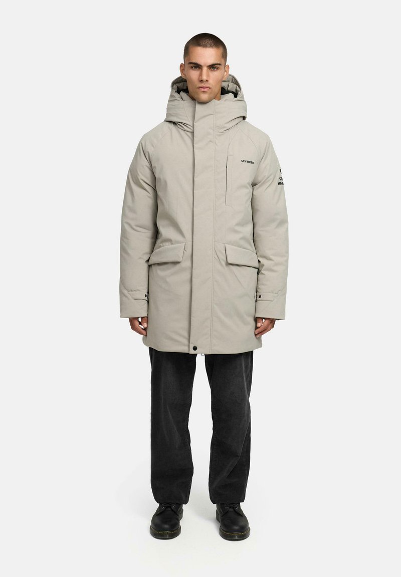 Gai pelēks spilvenveida parka ar augstu apkakli, lielām kabatām un kapuci. Dizains ir ar smalku zīmola atpazīstamību un taisnu siluetu.