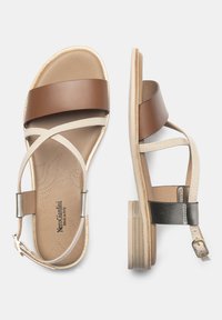 Sandali in pelle marrone e beige con cinturini incrociati, suola piatta, soletta testurizzata e dettagli metallici. Include una cinghia regolabile alla caviglia.