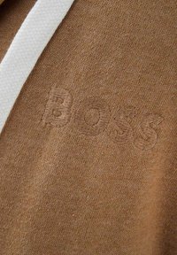 Felpa con cappuccio marrone in tessuto, con lacci bianchi e logo "BOSS" in rilievo dello stesso colore marrone. Materiale a maglia testurizzato.