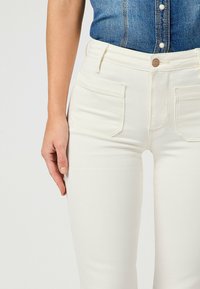 Valkoiset farkut, joissa on sileä pinta, slim fit -muotoilu, kahdella etutaskulla ja yhdessä nappisuljenta.