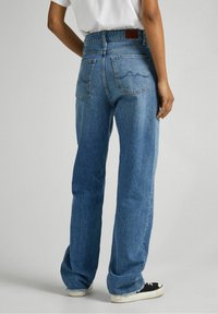 Light blue denim jeans with a loose fit, featuring a high waist, two back pockets, and a leather patch on the waistband.