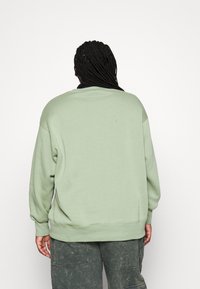 Grön oversized sweatshirt med ribbad rundhalsning och långa ärmar, tillverkad av mjukt tyg. Texturerad, lös passform med sänkta axlar.