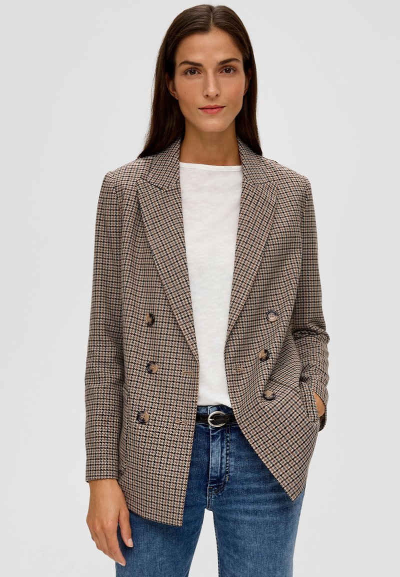 Doppeltknopfsakko im braunen und beigen Hahnentrittmuster, mit tailliertem Schnitt, Reverskragen und braunen Knöpfen. Tragen über einem weißen Oberteil.