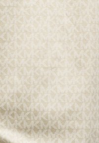 Tissu beige avec un motif géométrique répétitif de formes "K" gris clair, la texture semble lisse, uniforme et tissée serrée.