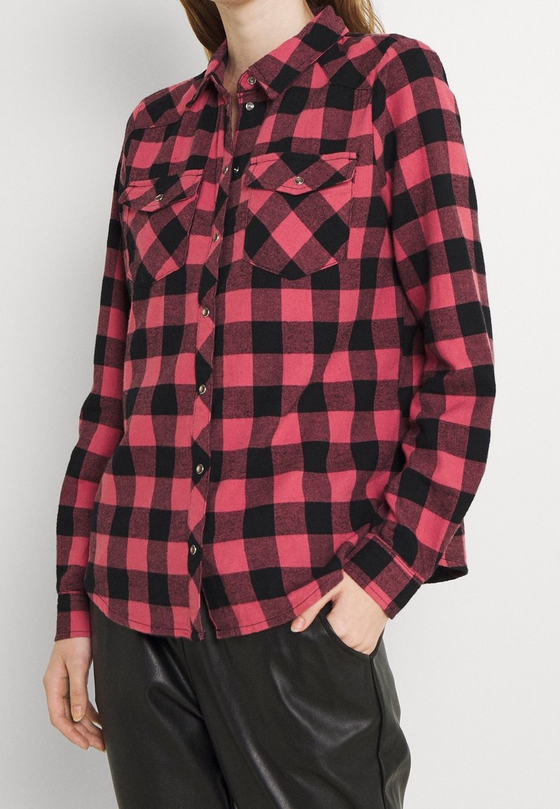 Red and black checkered flannel shirt with long sleeves, chest pockets, and button closure; features a rounded hemline and soft texture.