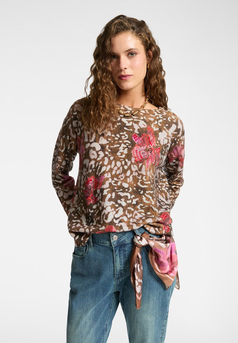 Maglione marrone lavorato a maglia con motivi floreali e animali, con maniche lunghe e una vestibilità rilassata. Abbinato a jeans in denim blu e a una sciarpa fantasia.