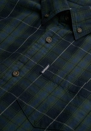 Camisa de franela a cuadros verde y azul marino con cuello abotonado, que cuenta con botones marrones y una etiqueta negra de "Superdry" en la parte delantera.