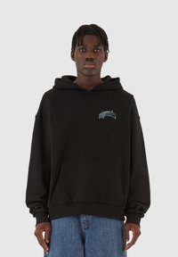 Svart hettegenser med frontlomme, ribbede mansjetter og brodert logo i lyseblått. Laget av et tykt bomullsmateriale.