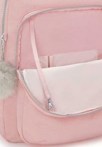 Rosa ryggsäck med en mjuk, vadderad textur, som har en zippered framficka, silverdetaljer och en avtagbar charm i fuskpäls med pom-pom.