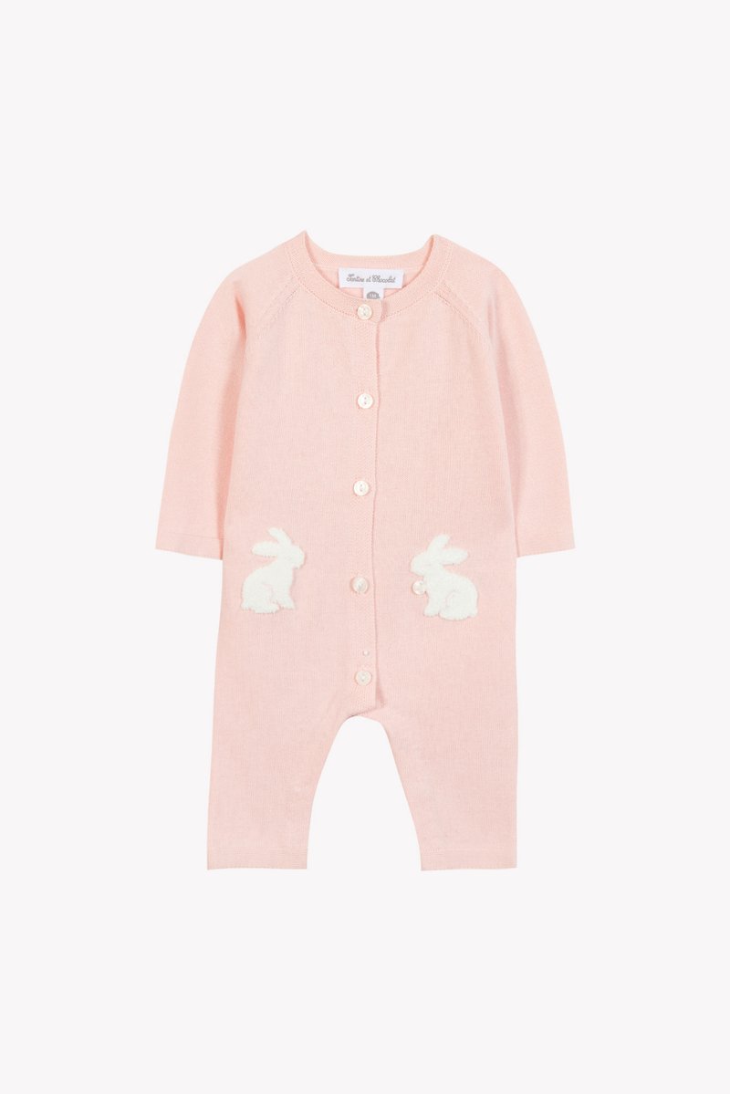 Ροζ πλεκτό βρεφικό ολόσωμο φορμάκι με μακριά μανίκια, που διαθέτει λευκές αφράτες εφαρμογές κουνελιού στις τσέπες και κλείσιμο με κουμπιά μπροστά.