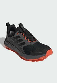 Schwarz-grauer Adidas Terrex Trailrunning-Schuh mit orangen Akzenten und robuster oranger Sohle, CLIMAPROOF-Schriftzug im Zehenbereich.