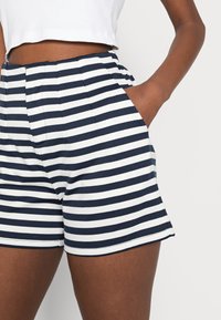 Marinblå och vita randiga shorts i bomullsblandning, med sidofickor och avslappnad passform. Figursydd midja med veck.