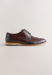 Chaussure brogue homme en cuir marron foncé avec détails perforés, fermeture à lacets et semelle en bois clair sur fond neutre.