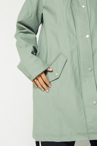 Light green waterproof coat with a high collar, snap buttons, and a patch pocket at the waist, featuring smooth texture and a relaxed fit.