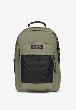 Mochila verde oliva con un bolsillo frontal de malla negra texturizada, asa superior y cierre de doble cremallera. Presenta un parche con el logo de Eastpak.