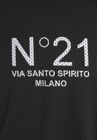 Černá síťovina s bílým tištěným textem: "N°21," "VIA SANTO SPIRITO," a "MILANO." Textura je prodyšná a s geometrickým vzorem.