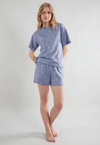 Hellblaues Pyjama-Set mit weißen Punkten. Kurzärmeliges Oberteil mit lockerem Schnitt und passende Shorts, gefertigt aus weichem Baumwollmaterial.