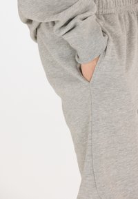 Helle graue Baumwollsweatpants haben eine Seitentasche und einen elastischen Bund, mit einer weichen Textur und einer lockeren Passform.