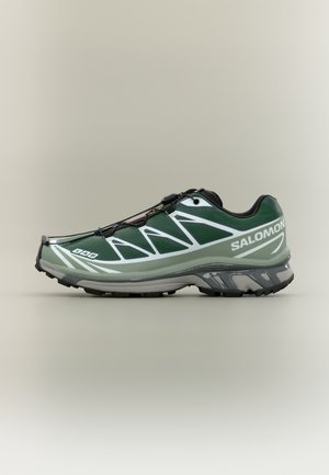 Scarpa sportiva verde con design elegante, tomaia in mesh traspirante, motivi strutturati e suola in gomma. Dotata di sistema di allacciatura rapida.