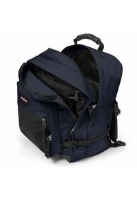 Tmavě modrý batoh s několika zipovými přihrádkami, černou síťovanou boční kapsou, polstrovanými ramenními popruhy a horním držadlem pro snadné přenášení.