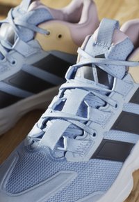Scarpe da atletica blu chiaro con tomaia in rete testurizzata, strisce nere di accento e collo imbottito. Presentano lacci piatti e suola in gomma.