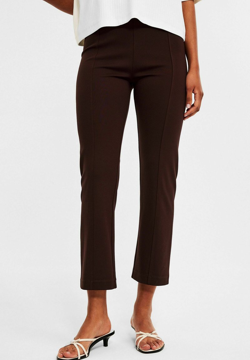 Braune, figurbetonte Hosen mit einem eleganten Design, hoher Taille und verkürzter Länge. Weiche Textur mit auffälligen Nähten.