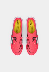 Φωτεινά ροζ παπούτσια ποδοσφαίρου με μαύρες λεπτομέρειες, υφή στην επάνω επιφάνεια και αεροδυναμικό σχέδιο. Διαθέτουν κίτρινη σόλα με κείμενο "ΝΕΟΣ ΠΡΟΔΟΤΗΣ".