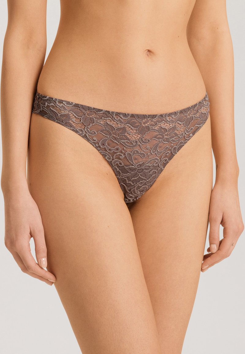 Lace string in gedempt bruin, met bloemmotieven, semi-doorschijnende stof en een comfortabele tailleband. Smooth textuur met delicate details.