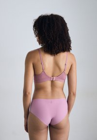 Ensemble de sous-vêtements rose clair comprenant un soutien-gorge doux et texturé avec des bretelles réglables et un slip assorti à la finition lisse.