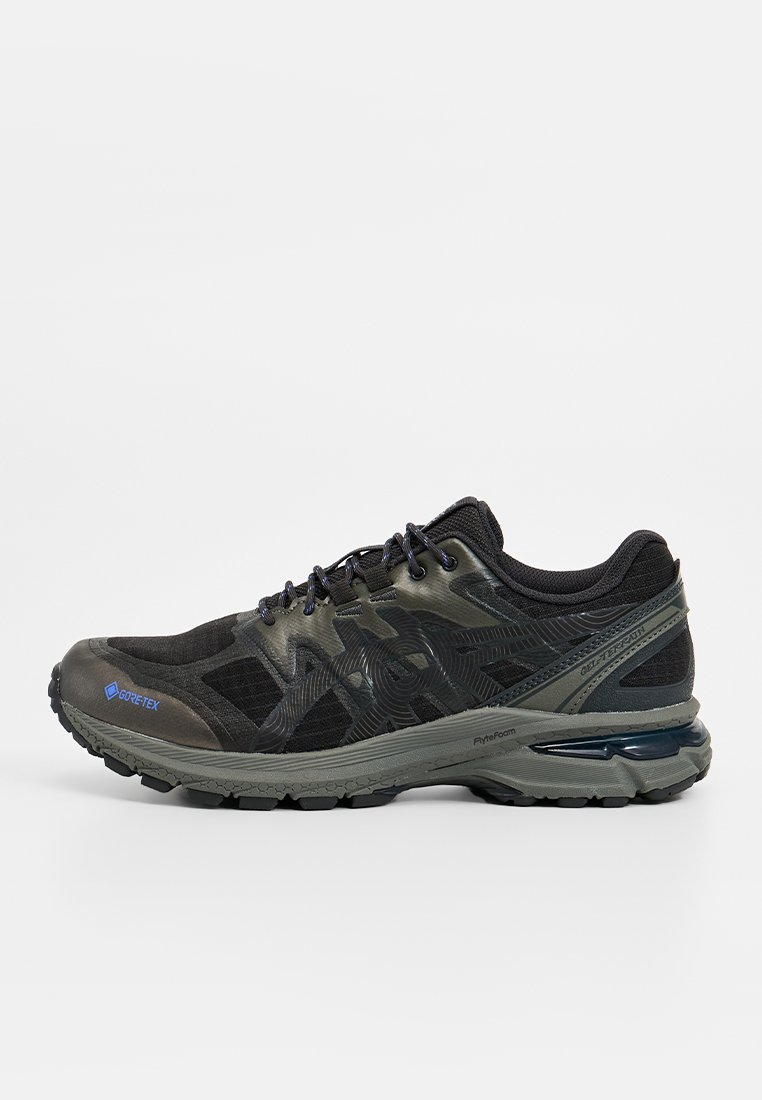 Schwarzer und olivgrüner Trailrunning-Schuh aus synthetischen Materialien. Verfügt über ein strukturiertes Design, Schnürsenkel und eine gepolsterte Sohle mit einem ausgeprägten Absatz.