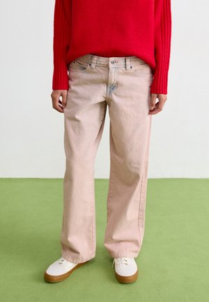 Light pink wide-leg jeans with a faded texture, paired with a red ribbed sweater and white sneakers, set against a green floor.