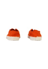 Des chaussures slip-on en toile orange avec une semelle en caoutchouc blanche, présentant une surface texturée et des détails effilochés le long des bords.