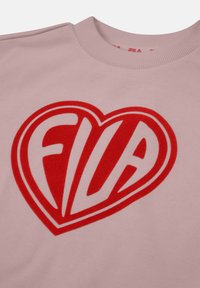 Sudadera rosa claro con un gran gráfico de un corazón rojo que presenta el logo "FILA" en blanco. Cuello redondo acanalado y textura de tela suave.