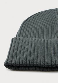 Dark gray knitted ribbed beanie with folded cuff laid flat on white background.