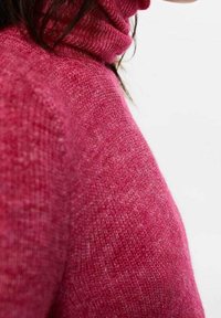 Pull-over en maille texturée rose avec un col roulé haut. Accent sur le tissu doux et chaud ainsi que sur les détails de surface lisses.